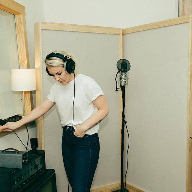 A woman wearing headphones in a recording studio, immersed in music.