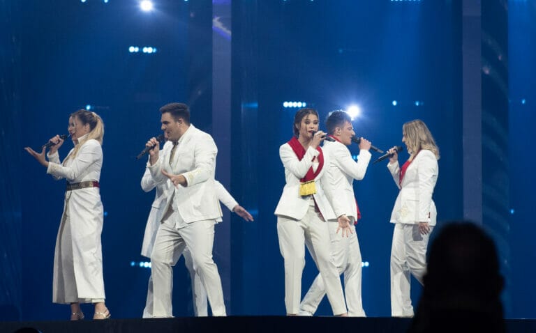 A group of people in white suits performing on stage.