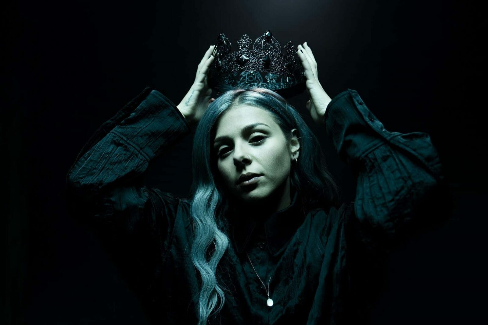 Woman, blue hair, holding crown.