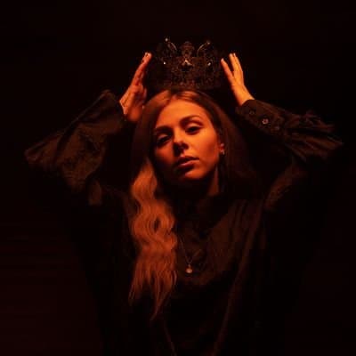 A woman in black wearing a regal crown on her head.