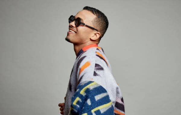 A man wearing sunglasses and a vibrant sweater.