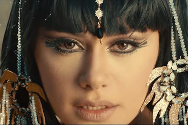 A woman adorned in Egyptian jewelry, with black hair flowing gracefully.